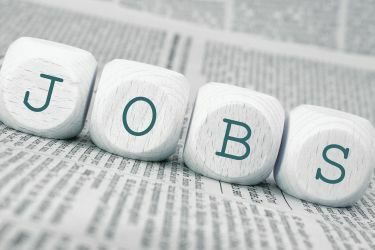 Offene Stellen. Buchstabenwürfel auf einer Zeitung bilden den Begriff Jobs